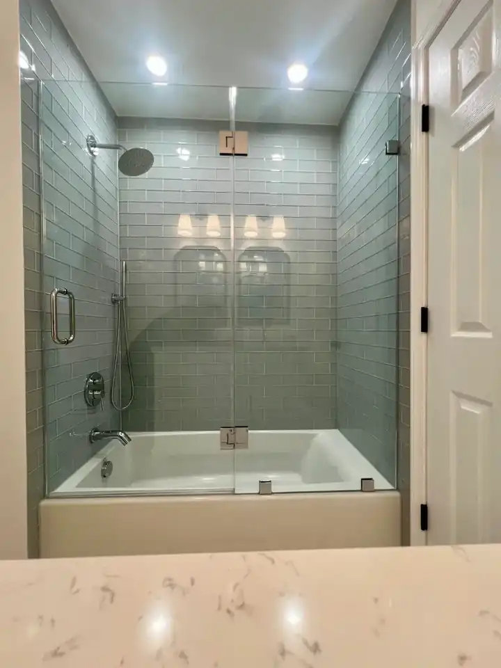 Finished bathroom with glass tub enclosure, blue wall tile, recessed lighting, white doors, and patterned floor