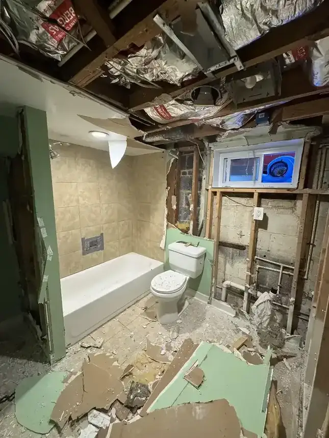 Bathroom renovation progress with open wall framing and exposed work area beside tub and toilet