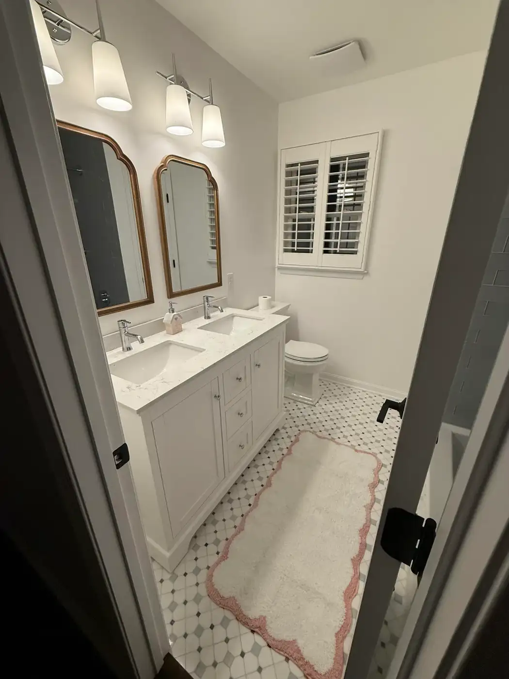 Finished bathroom with white vanity, double mirrors, patterned floor, lighting, and toilet