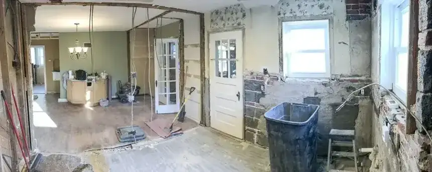 Interior room renovation progress with drywall repair, open floor protection, and finish prep