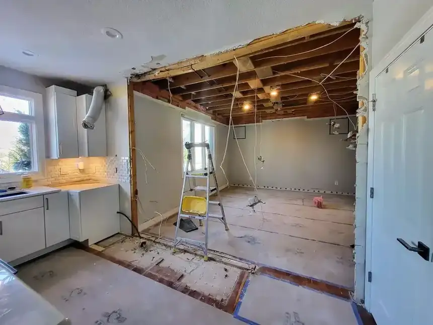 Kitchen renovation progress with removed ceiling area, work lighting, and open floor area