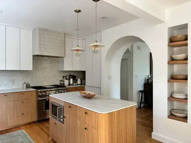 Finished kitchen with wood island, light cabinetry, arched opening, and open shelving
